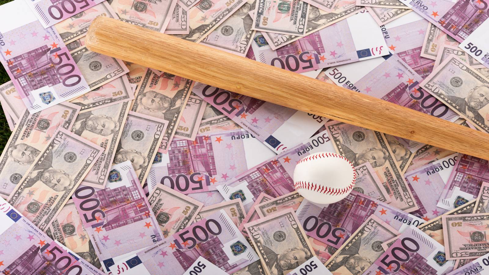 A baseball bat and baseball on top a pile of money