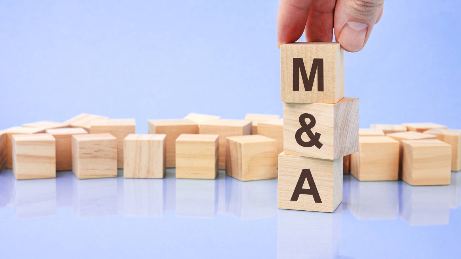 Hand holding wood cube block with M and A text