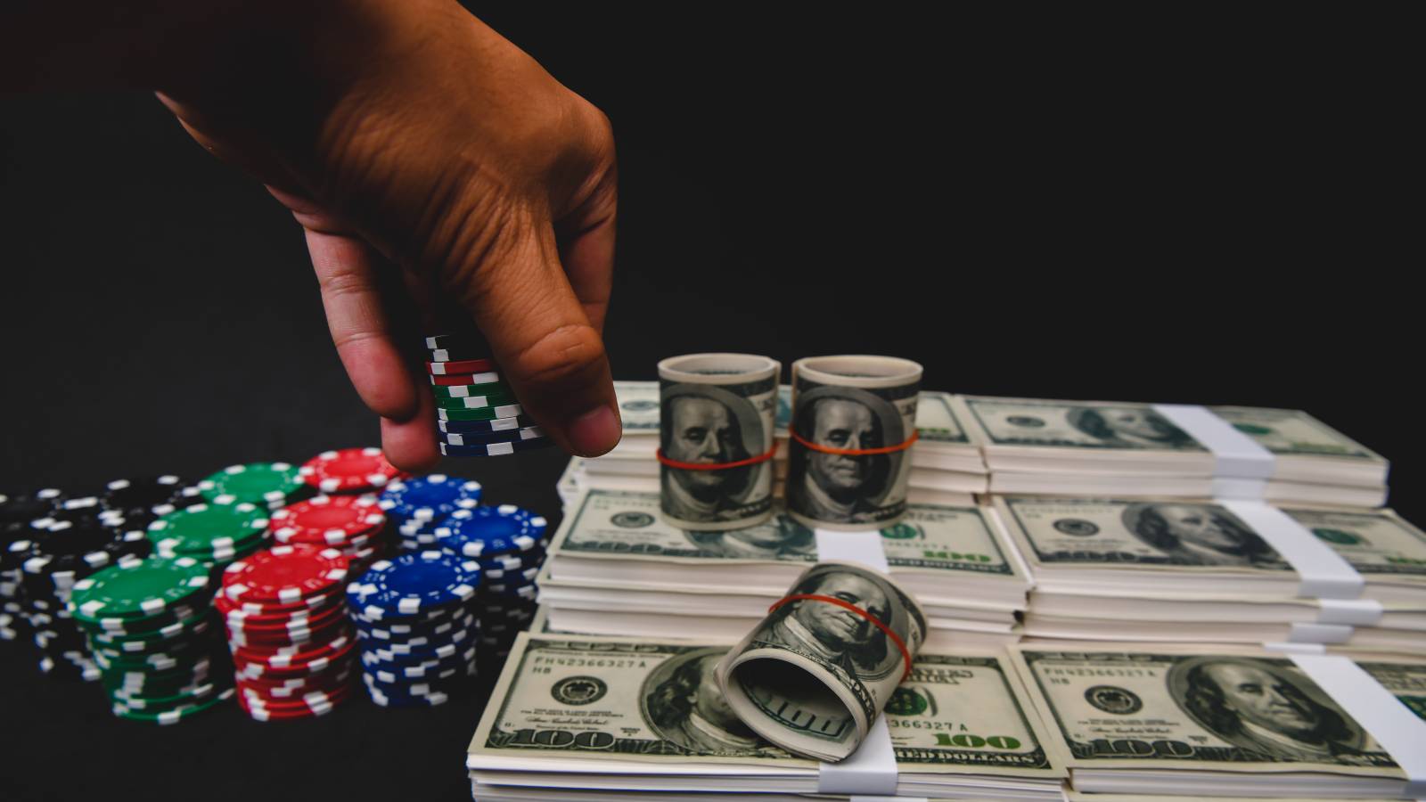 A man holding casino chips over a stack of cash