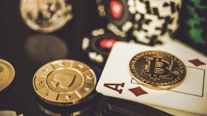 A Bitcoin gold coin on the ace of diamonds, surrounded by out of focus casino chips.