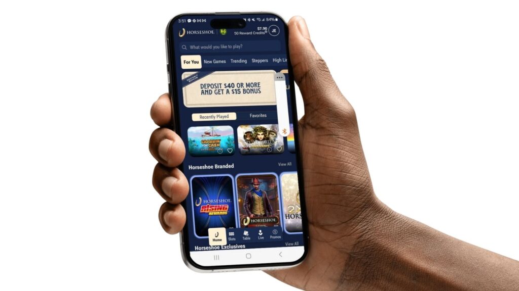 Horseshoe Online Casino homepage on a smartphone screen mockup, held by a male hand.